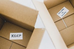 decluttering concept, storage boxes to sort between objects to keep and those to declutter or donate with labels, moving guide